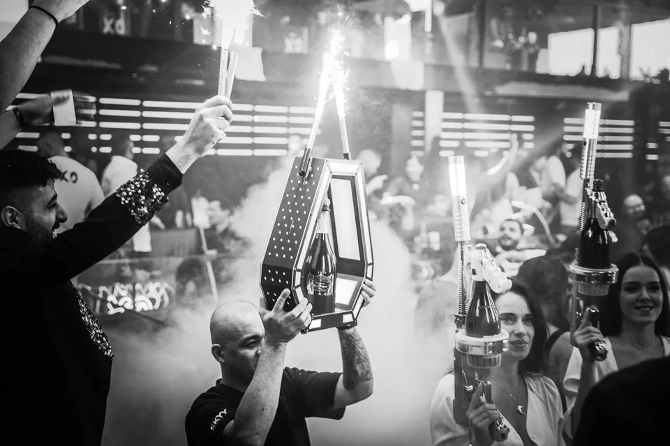 A black and white shot of a bottle service parade with sparklers at XO Club Dubai