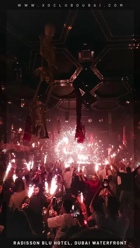 A crowd lit by sparklers and pink light at XO Club Dubai
