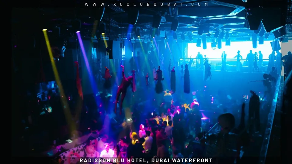 Aerial performers above the crowd in blue light at XO Club Dubai