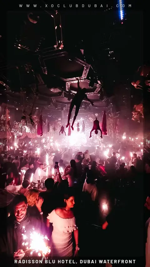 Guests holding sparklers under aerial performers at XO Club Dubai