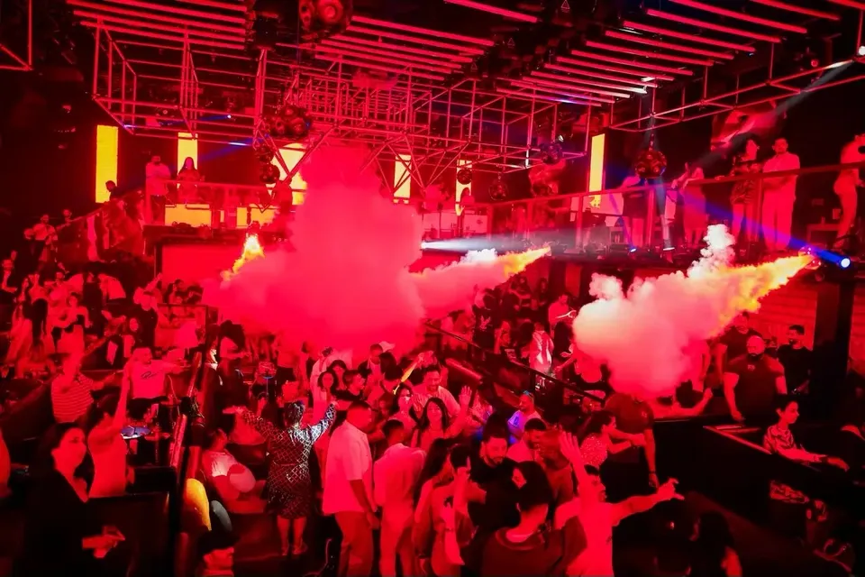 Smoke cannons firing over a packed room in red light at XO Club Dubai